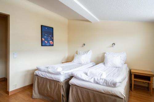 two beds in a room with white sheets at Hiisi Hotel Turku Seaport in Turku