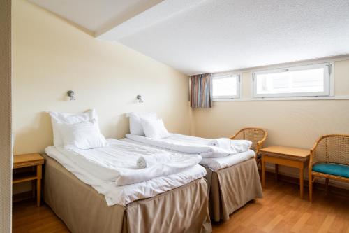 two beds in a room with two chairs and a window at Hiisi Hotel Turku Seaport in Turku