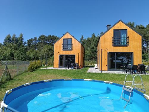 una casa con piscina delante de ella en Relakstacja - domki z sauną i balią, en Mieroszyno