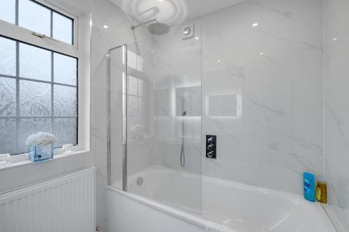 a white bathroom with a shower and a window at Stylish 3BR House Close to Wembley Stadium and Arena in London