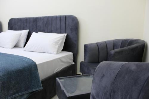 een slaapkamer met een bed en een stoel bij Islamabad Comfort Inn in Islamabad