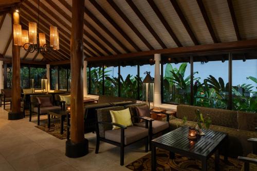 a living room with chairs and tables and windows at EKHO Surf Bentota in Bentota