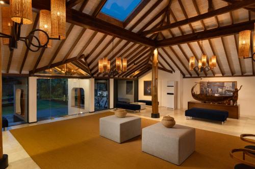 a living room with couches and chairs and a ceiling at EKHO Surf Bentota in Bentota