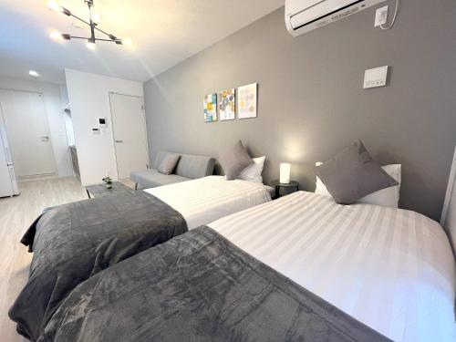 a bedroom with two beds and a couch at Naos House Hotel Osaka 5 in Osaka