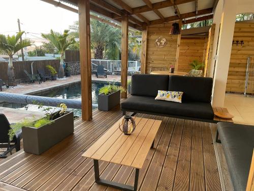 a patio with a black couch on a wooden deck at Harmonie de 3 logements- Villa des 4 Sens in Le Tampon