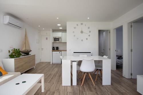 a kitchen and living room with a white table and chairs at Apartament amb piscina i aparcament - Baixos amb jardinet in Calella de Palafrugell