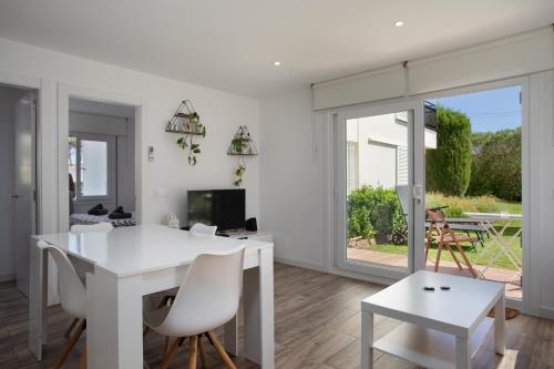 a white dining room with a white table and chairs at Apartament amb piscina i aparcament - Baixos amb jardinet in Calella de Palafrugell