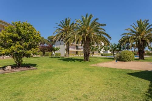 a park with palm trees and a building at Apartament amb piscina i aparcament - Baixos amb jardinet in Calella de Palafrugell