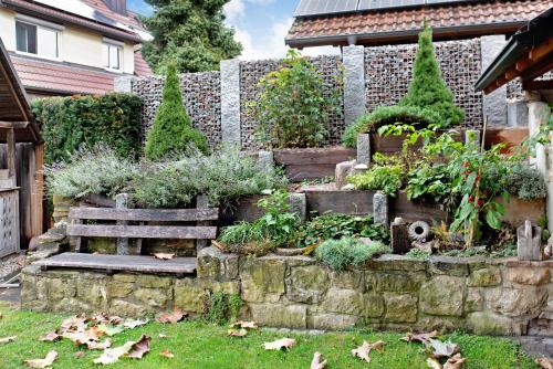 a garden with a bench and a stone wall at Ferienwohnung Atelier in Bad Bellingen