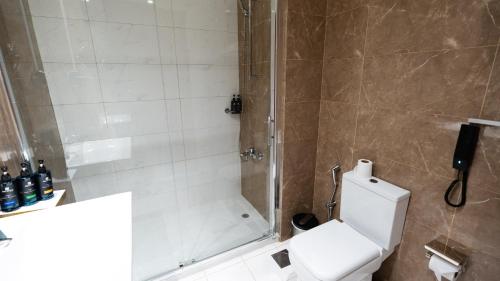 a bathroom with a shower and a white toilet at Acacia Hotel by Blue Collection in Ras al Khaimah