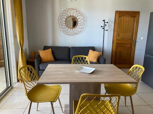 a table and chairs in a living room with a couch at Harmonie de 3 logements- Villa des 4 Sens in Le Tampon