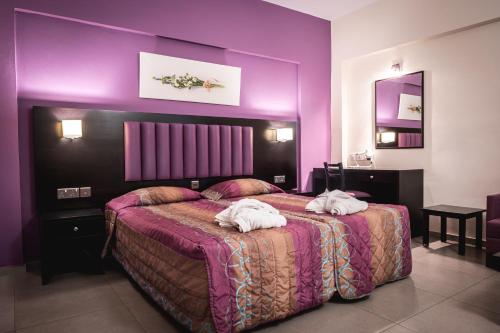 a purple bedroom with a bed with two towels on it at Kefalos Damon Hotel Apartments in Paphos City