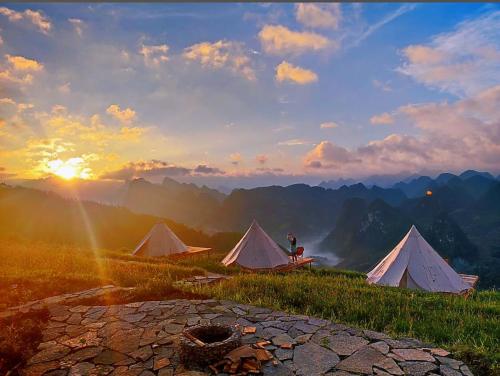 a person sitting in front of tents on a mountain at Sunrise Ha Giang Camping An Introspective Stay in Kon Rung (1)