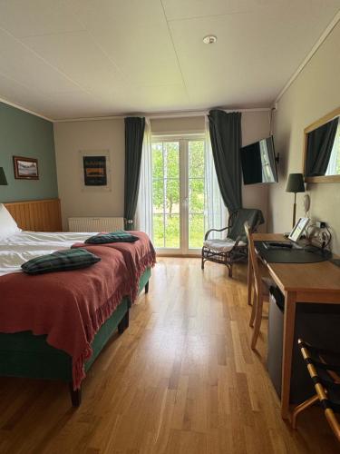 トローサにあるTrosa Åda Krog Hotell & Konferensのベッドと机と窓があるホテルの部屋