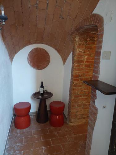 a room with a table and two red stools at Le Stanze del Ritrovino in Castiglione dʼOrcia