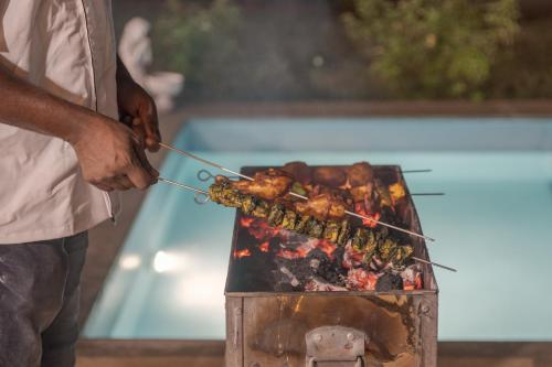 a man is cooking food on a grill at SaffronStays Roselle, Malavli - pet-friendly pool villa with modern interiors in Lonavala