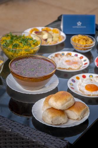 a table with plates of food and bowls of food at SaffronStays Roselle, Malavli - pet-friendly pool villa with modern interiors in Lonavala