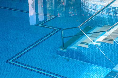 a blue swimming pool with a stair in the water at Elfordleigh Hotel in Plymouth