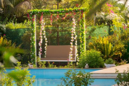 a pergola with a bench in a garden at SaffronStays Roselle, Malavli - pet-friendly pool villa with modern interiors in Lonavala