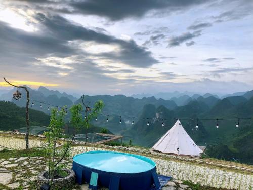 a tent and a table with a view of mountains at Sunrise Ha Giang Camping An Introspective Stay in Kon Rung (1)