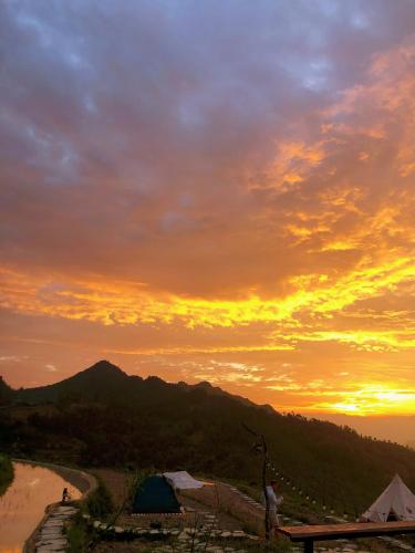 a view of a sunset with a tent and mountains at Sunrise Ha Giang Camping An Introspective Stay in Kon Rung (1)