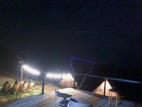 a table and chairs on a deck at night at Sunrise Ha Giang Camping An Introspective Stay in Kon Rung (1)
