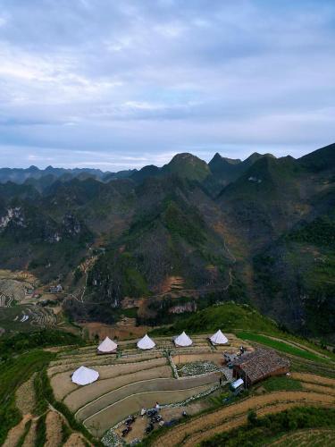 an aerial view of a farm with mountains in the background at Sunrise Ha Giang Camping An Introspective Stay in Kon Rung (1)