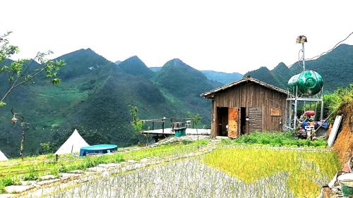 a house on a hill with mountains in the background at Sunrise Ha Giang Camping An Introspective Stay in Kon Rung (1)