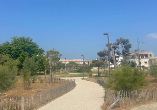 a walking path in a park with trees and buildings at Hôtel Le Carnon in Carnon-Plage