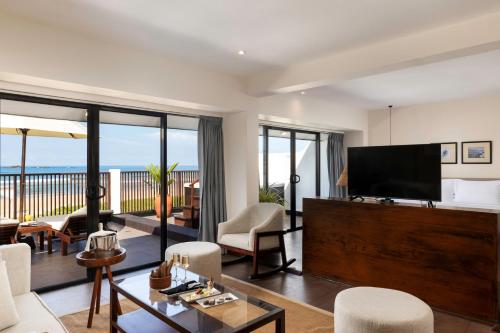 a living room with a television and a balcony at EKHO Surf Bentota in Bentota