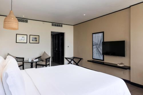 a bedroom with a white bed and a flat screen tv at EKHO Surf Bentota in Bentota