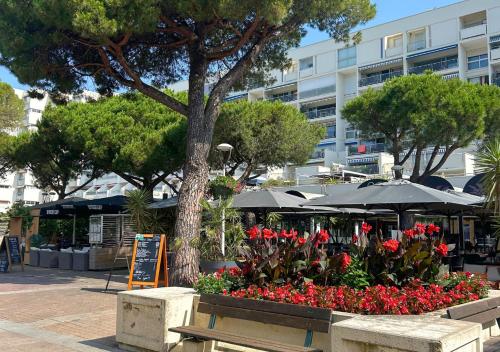a park with flowers and umbrellas in front of a building at Hôtel Le Carnon in Carnon-Plage
