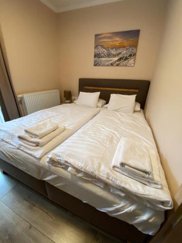 a large bed with white sheets and towels on it at Nockalm Cottage in Bad Kleinkirchheim