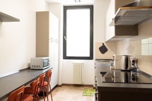 a kitchen with a counter with chairs and a microwave at BERNINA STATION CENTRE APARTMENT 3 - three minutes walk from bernina station in Tirano