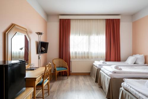 a hotel room with two beds and a desk and a television at Hiisi Hotel Turku Seaport in Turku