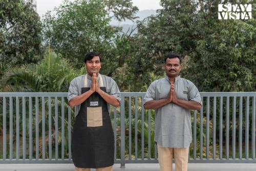 two men standing in front of a fence praying at Eden Springs by VEO - Part of StayVista in Karjat