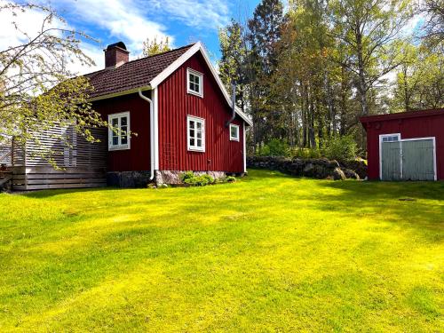 a red house in a yard with a green lawn at Villa Riksberg near Götakanal in Töreboda