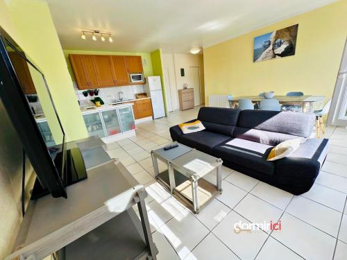 un salon avec un canapé bleu et une cuisine dans l'établissement L'Ancre de Royan - clim, plage à pied, 6pers, à Royan