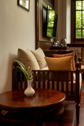 a couch with pillows and a vase on a table at Hotel Suisse Kandy - Since 1890 in Kandy