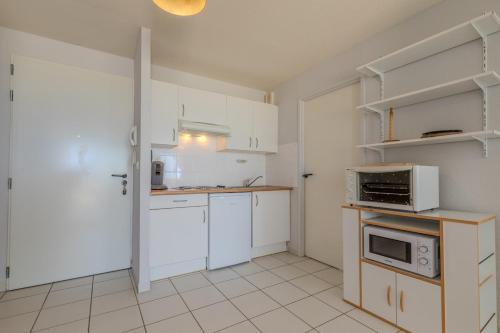 Una cocina con gabinetes blancos y un microondas. en Vue imprenable sur l'océan, en Vieux-Boucau-les-Bains