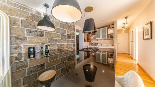 Una cocina con pared de piedra y lámparas colgantes. en villa frontlake, en Tresserves