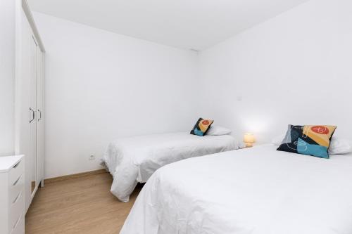 two beds in a room with white walls and wooden floors at Home2Book Sunny Rooftop Duplex, Puerto del Rosario in Puerto del Rosario