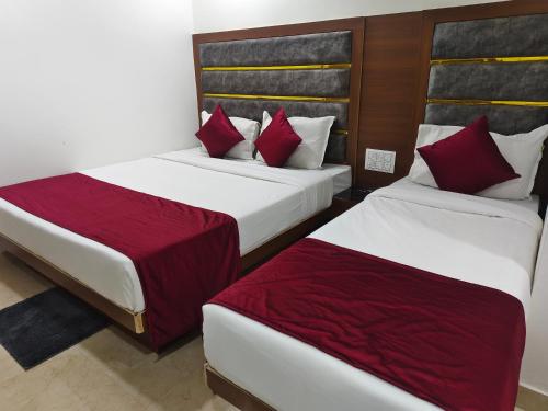 two beds in a hotel room with red pillows at Hotel MARUTI R Drive Inn Road in Ahmedabad