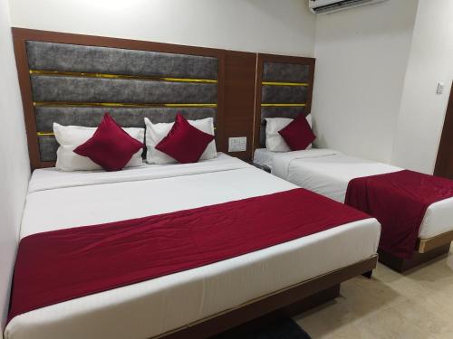 two beds in a hotel room with red pillows at Hotel MARUTI R Drive Inn Road in Ahmedabad