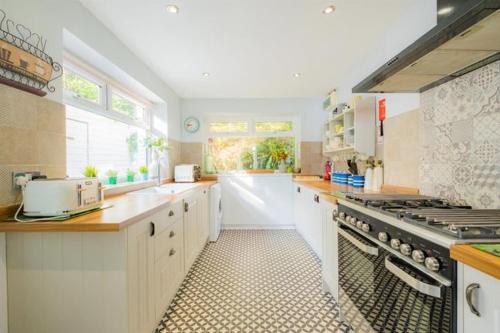 a large kitchen with white cabinets and a stove at Cornwall Large Beach House Sea & Beach Views - 4 Bedrooms & 3 Bathrooms in Looe
