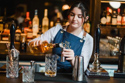 a woman pouring a drink at a bar at The Royal Sutton in Sutton Coldfield