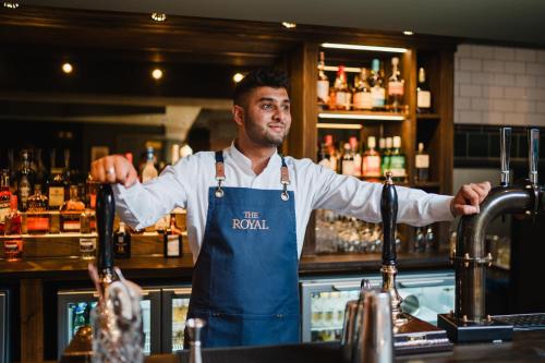 a man standing behind a bar with his arms outstretched at The Royal Sutton in Sutton Coldfield
