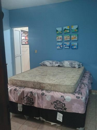 a bedroom with a bed with a blue wall at Ambiente Familiar in Ubatuba