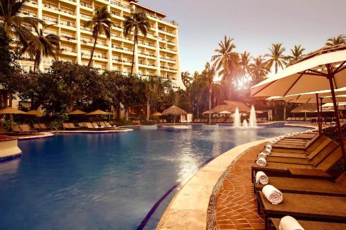 a large swimming pool with chairs and a large building at Fiesta Americana Puerto Vallarta All Inclusive & Spa in Puerto Vallarta