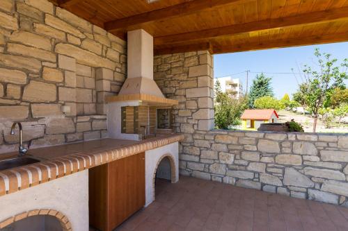 una cocina al aire libre con una pared de piedra en Diamantis Villa, a SeaView Retreat, By ThinkVilla, en Adelianos Kampos